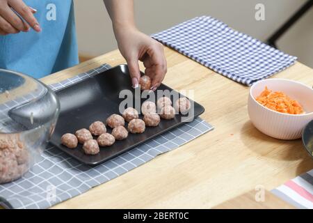 Young woman cooking in kitchen. Housewife preparing vegetables for cooking. Making fresh meat balls . Cooking soup Stock Photo