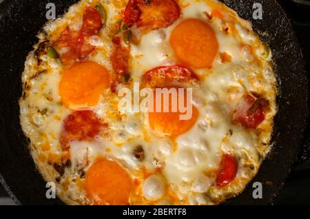 Fried eggs with tomatoes in a pan close-up Stock Photo