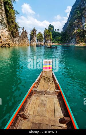 Wooden traditional Thai longtail boat on Cheow Lan Lake in Three Rocks landmark, Khao Sok National Park, Thailand