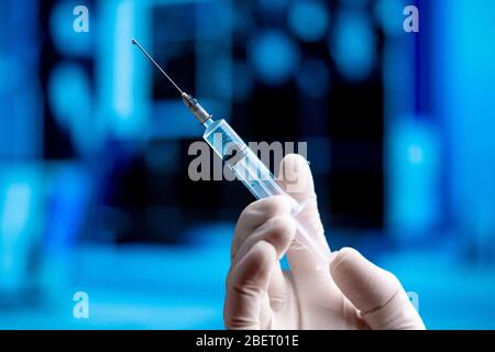 Doctor Hand in White Gloves Holding Syringe With Vaccine Before Immunization and Vaccination. Medicine From SARS Coronavirus, 2019-nCoV In Blue Labora Stock Photo