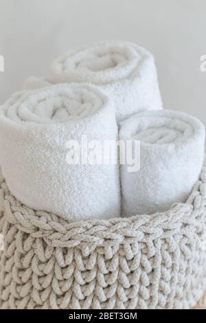 Rolled soft towels in basket on white background. Close up. Stock Photo