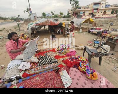 Beawar, India. 14th Apr, 2020. A poor man reading newspaper at slum area during nationwide lockdown in the wake of coronavirus pandemic in Beawar. (Photo by Sumit Saraswat/Pacific Press) Credit: Pacific Press Agency/Alamy Live News Stock Photo