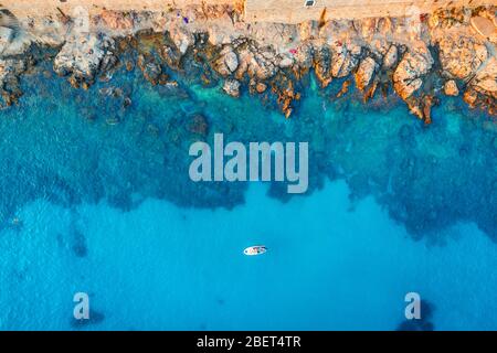 Aerial view of beach with stones and rocks, alone boat in the sea