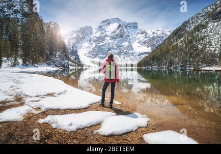 Young woman with backpack on the snowy shore of Braies lake Stock Photo