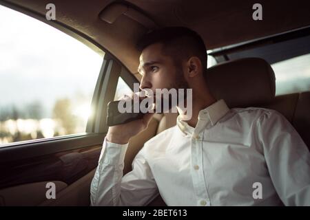 Man looking away while sitting on the back seat of a car, businessman in taxi Stock Photo