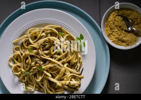 Vegan pasta dish. Fettuccine with pesto, green olives fresh thyme and Nutritional yeast. Stock Photo