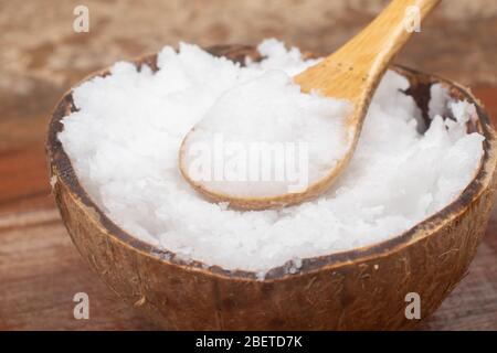 Coconut oil in the coconut bowl over a wooden table Stock Photo