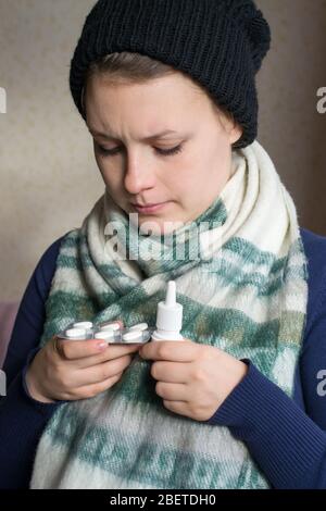 Sick girl holding a spray from the cold and a pills Stock Photo