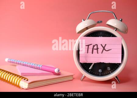 tax time sticky notes on alarm clock on pink background. Stock Photo