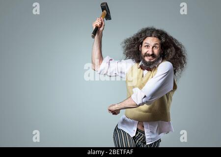 Portrait of an eccentric, aggresive nerd holding a hammer Stock Photo