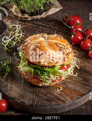 Vegetarian burger with fresh radish and fenugreek sprouts, broccoli microgreens, lettuce and tomatoes Stock Photo