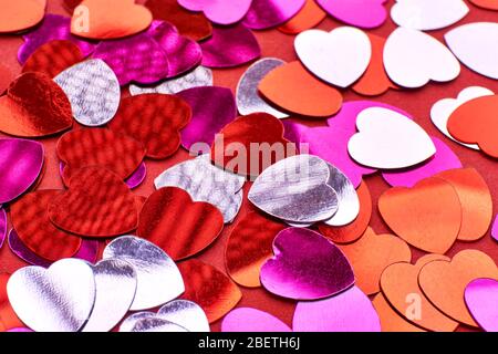 Heart background, Close up of shiny heart shaped confetti in red, pink, orange and silver for use as a holiday, valentine or birthday background. Stock Photo