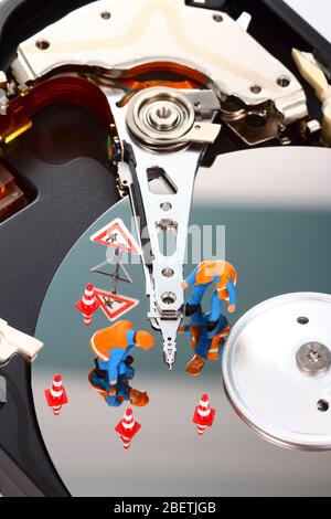 Conceptual image of miniature figure people looking for problems on a computer hard drive