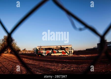 Abandoned passenger truck in La Manga neighborhood. seen through steel mesh fence.   Camion de pasajeros abandonado en la colonia la Manga. visto trav Stock Photo