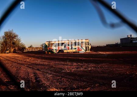 Abandoned passenger truck in La Manga neighborhood. seen through steel mesh fence.   Camion de pasajeros abandonado en la colonia la Manga. visto trav Stock Photo