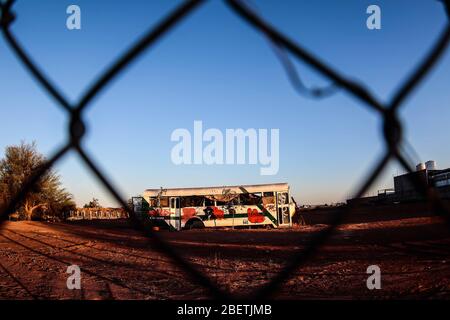 Abandoned passenger truck in La Manga neighborhood. seen through steel mesh fence.   Camion de pasajeros abandonado en la colonia la Manga. visto trav Stock Photo