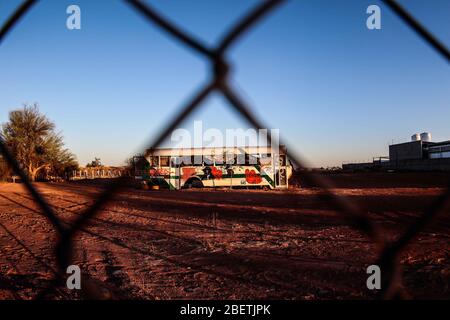 Abandoned passenger truck in La Manga neighborhood. seen through steel mesh fence.   Camion de pasajeros abandonado en la colonia la Manga. visto trav Stock Photo