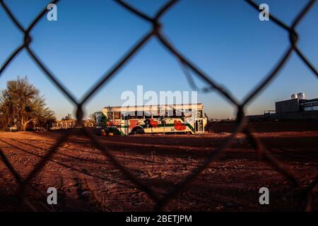 Abandoned passenger truck in La Manga neighborhood. seen through steel mesh fence.   Camion de pasajeros abandonado en la colonia la Manga. visto trav Stock Photo