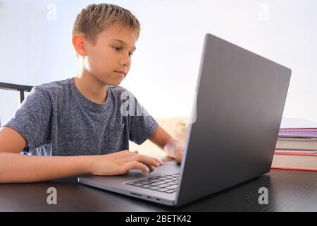 Preteen boy using laptop computer at home. Technology, online learning, distance education, home studying, homework, educational games for kids Stock Photo
