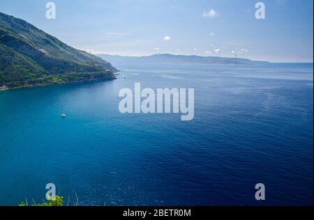 Aerial top view of green hill and harbour of beautiful seaside town village Scilla, Tyrrhenian sea bay gulf coast shore, Sicilia island and blue sky b Stock Photo