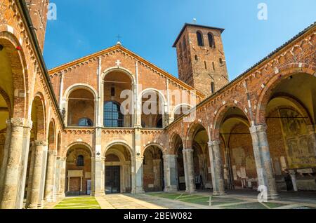 Basilica of Sant'Ambrogio church brick building with bell towers, courtyard, arches, blue sky background, Milan, Lombardy, Italy Stock Photo