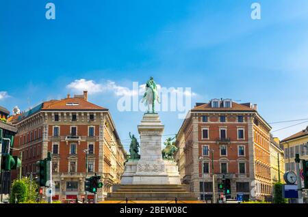 Monument Giuseppe Garibaldi statue on Largo Cairoli square rear view and old traditional buildings in beautiful summer day, blue clear sky background, Stock Photo