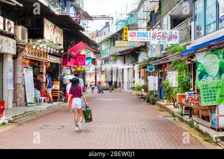 Hong Kong, Hong Kong SAR - July 14, 2017: Residents and visitors stroll along the main street in old town Sai Kung village. The laidback seaside town Stock Photo