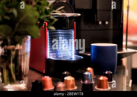 Red Blue Glowing Coffee Machine with Capsules in the Foreground Stock Photo