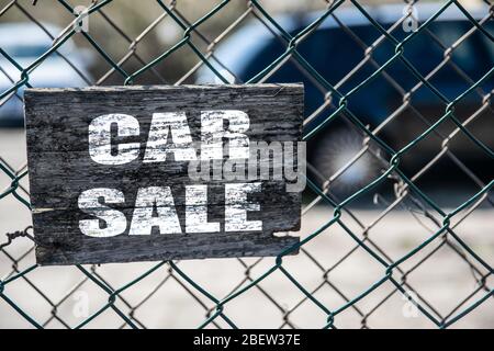 Old cracked rectangular wooden plate on the old green mesh fence with the inscription Car Sale Stock Photo