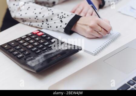 The girl is engaged in accounting. Woman's hand writes in a notebook home expenses and income. The concept of the distribution of cash, compliance wit Stock Photo
