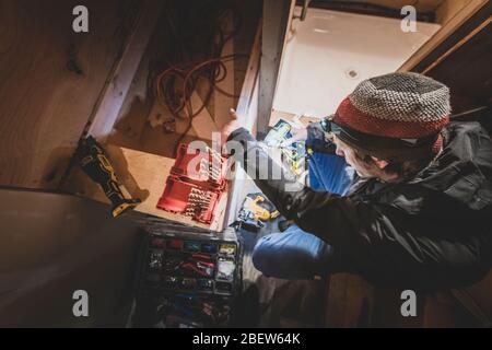 View from top of man drilling in wood while doing a bus conversion Stock Photo