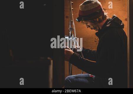 Side view of handyman working on installing a shower, bus conversion Stock Photo