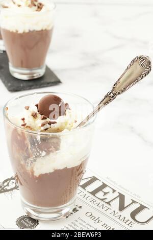 Chocolate mousse and cream cup half empty on white marble background.Food elegant restaurant menu concept Stock Photo