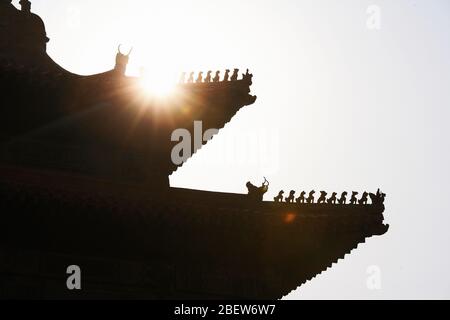 the sun rises over a rooftop in the forbidden city Stock Photo