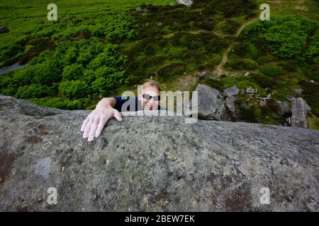 climber topping out from a climb at Stanage edge in the Peak District Stock Photo