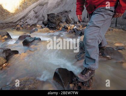 partial view of woman crossing stream in Landmannalauga Stock Photo