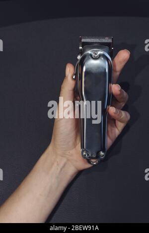 An electric shaver is on black background. Hand is holding razor for men. Stock Photo