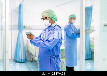 Asian doctor man using digital tablet and doctor team clinic personnel wearing face mask in hospital while Coronavirus outbreak. Stock Photo