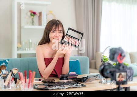 Asian woman vlogger present or teaching make up beauty cosmetic product or her face and broadcast live video to social network by internet at home, be Stock Photo