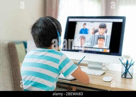 Asian boy student video conference e-learning with teacher and classmates on computer in living room at home. Homeschooling and distance learning ,onl Stock Photo