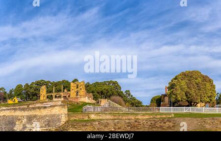 View of Smith O'Brians cottage, hospital ruins with stone wall surrounds next to wooden picket fence bordering the Canadian Cottage at Port Arthur. Stock Photo