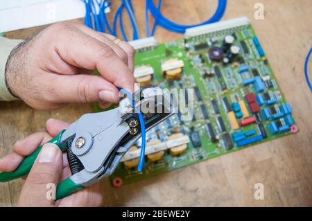 an electric technician with an electronic board performing maintenance as part of a skilled job workforce in the electric power industry Stock Photo