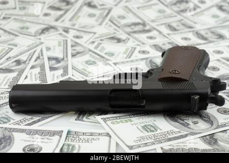 Black gun pistol on stack money 100 dollars background Stock Photo