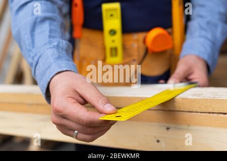 Close up picture of carpenters hands measuring plank - DIY renovation at home Stock Photo
