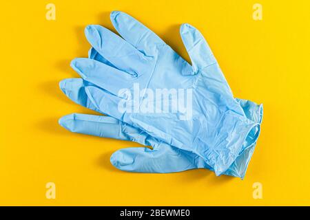 A pair of new blue latex protective gloves isolated on a yellow background. Blue surgical gloves. Concept of medicine health care. Stock Photo