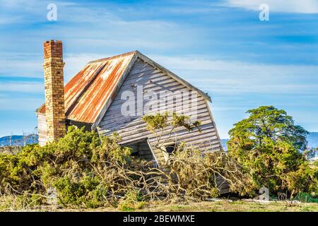 An abandoned, pioneer settler farmhouse on a hillside along the Tamar River in Tasmania. Stock Photo