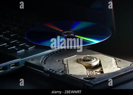 CD on the computer notebook cd rom in darkness. Concept of technological advances in computer data recording systems. Stock Photo