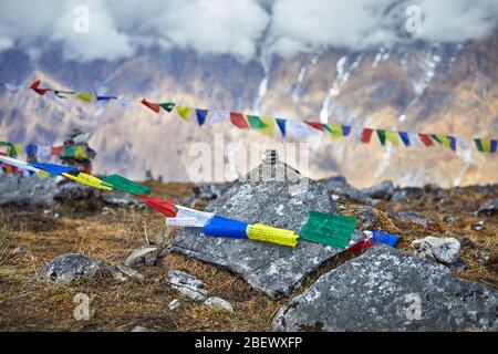 Small piles from stones and Tibetan prayer flags Lung Ta at the Mardi Himal Base Camp at cloudy peaks of Himalaya Mountains in Nepal Stock Photo