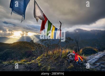 Small piles from stones and Tibetan prayer flags Lung Ta at the Mardi Himal Base Camp at cloudy sunset peaks of Himalaya Mountains in Nepal Stock Photo