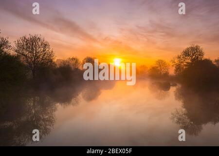 Wimborne, Dorset, UK.  16th April 2020.  UK Weather.   A spectacular sunrise is reflected in River Stour at Eye Bridge at Wimborne in Dorset with mist rising from the water.  Picture Credit: Graham Hunt/Alamy Live News Stock Photo